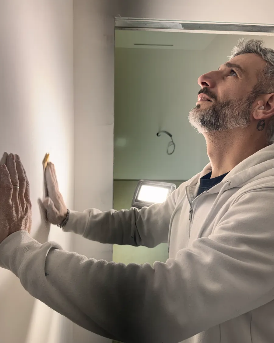 Michele Iurianello controlla una parete con la mano, la luce radente accesa a terra